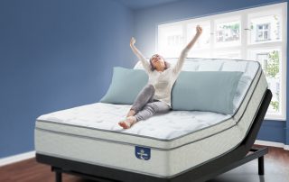 Girl sitting on an adjustable bed in a blue room.