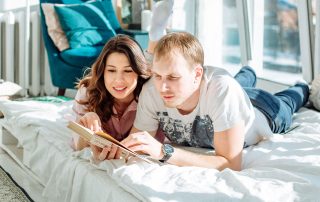 Couple in bed reading a book together.