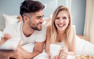 Couple in bed enjoying their time together with breakfast and a television show.
