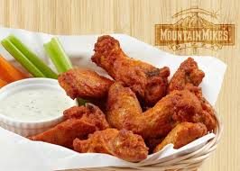 Mountain Mike's chicken wings with ranch, celery, and carrots on a wooden texture background.