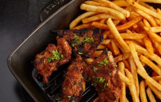 Image of grilled chicken and fries on a tray for Backyard Bayou.