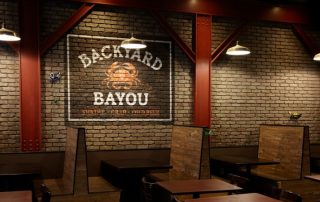Backyard Bayou image of inside the restaurant with lined up booths and logo on the wall. 